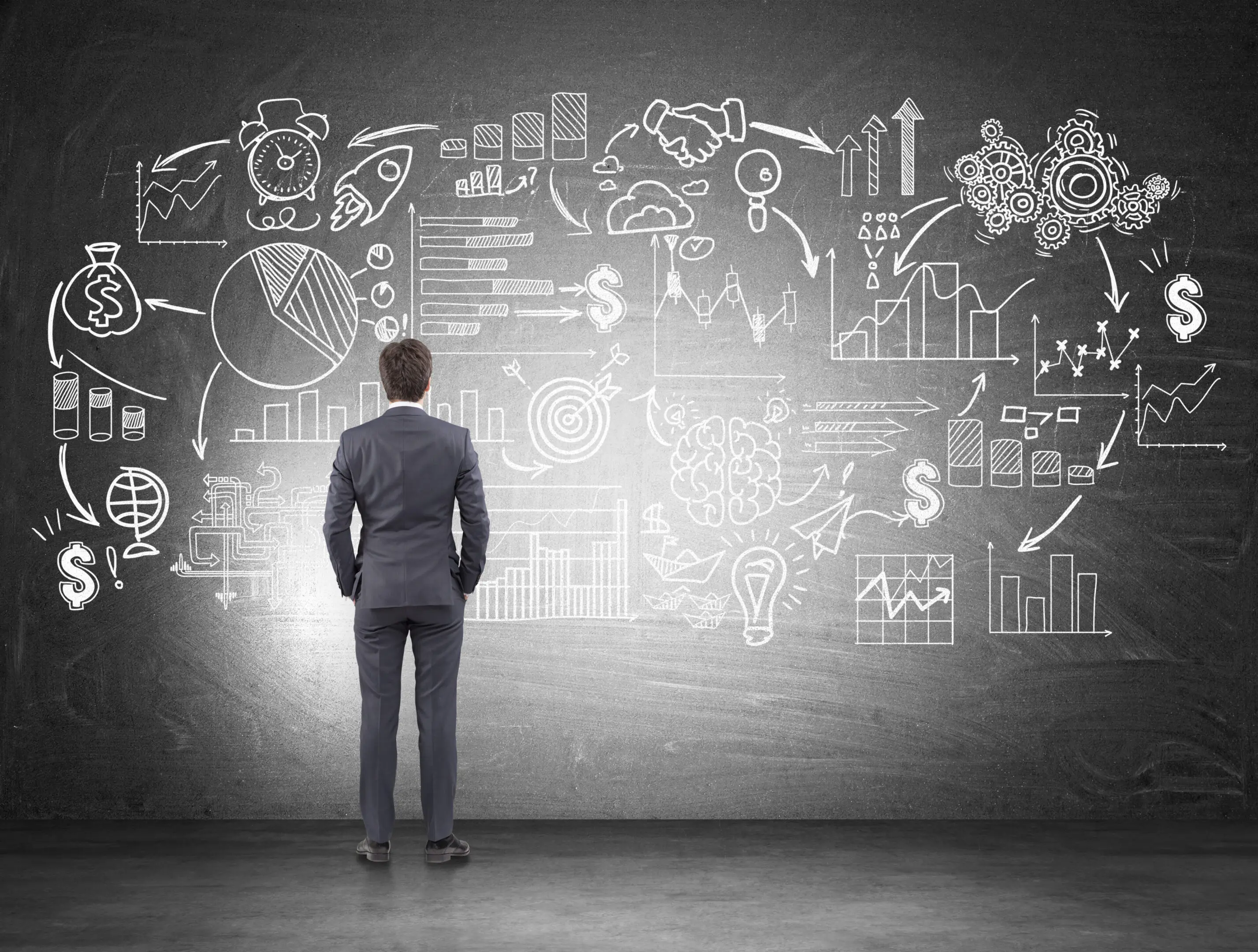 Rear view of man looking at business scheme A man in a suit standing next to a wall with many drawings on it.