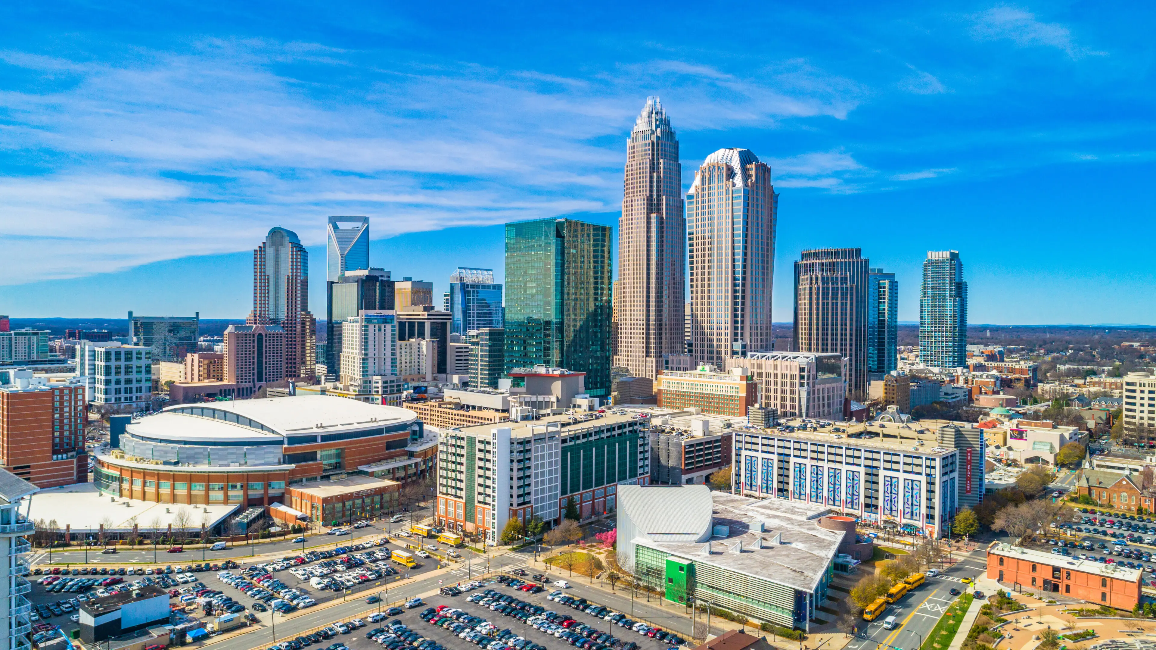 A city with many buildings and cars parked in the parking lot.
